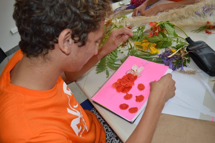jovem em clase fazendo um croqui de moda com flores de verdade