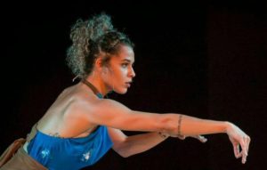 figurino de espetáculo mulher loira de cabelos cacheados com frente única azul olhando para frente