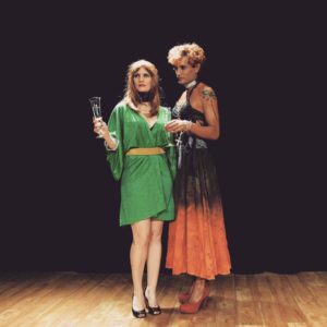 mulher vestida com vestido verde segurando uma taça e um homem vestido de mulher