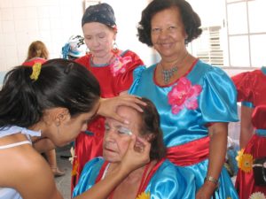 mulheres se preparando para o carnaval uma sendo maquiada e outras duas experando