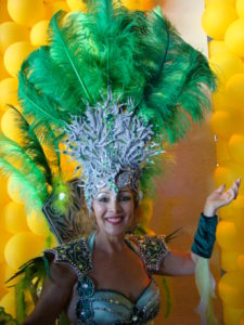 mulher com adereço de cabeça pratiado e plumas verdes toper bordado e ombreira e costeiro de carnaval