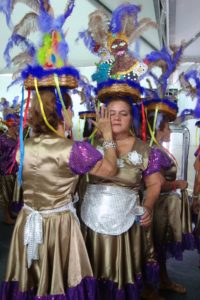 duas mulheres vestidas de fantasia de carnaval e com adereço de cabeça uma está maquiando a outra