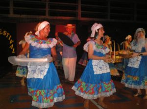 grupo de pessoas vestidos com figurino folclórico dançando e segurando cestas com frutas