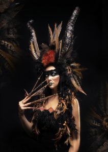 mulher vestida de deusa demoníaca com chifres flumas e unhas acrícilas artísticas nail art