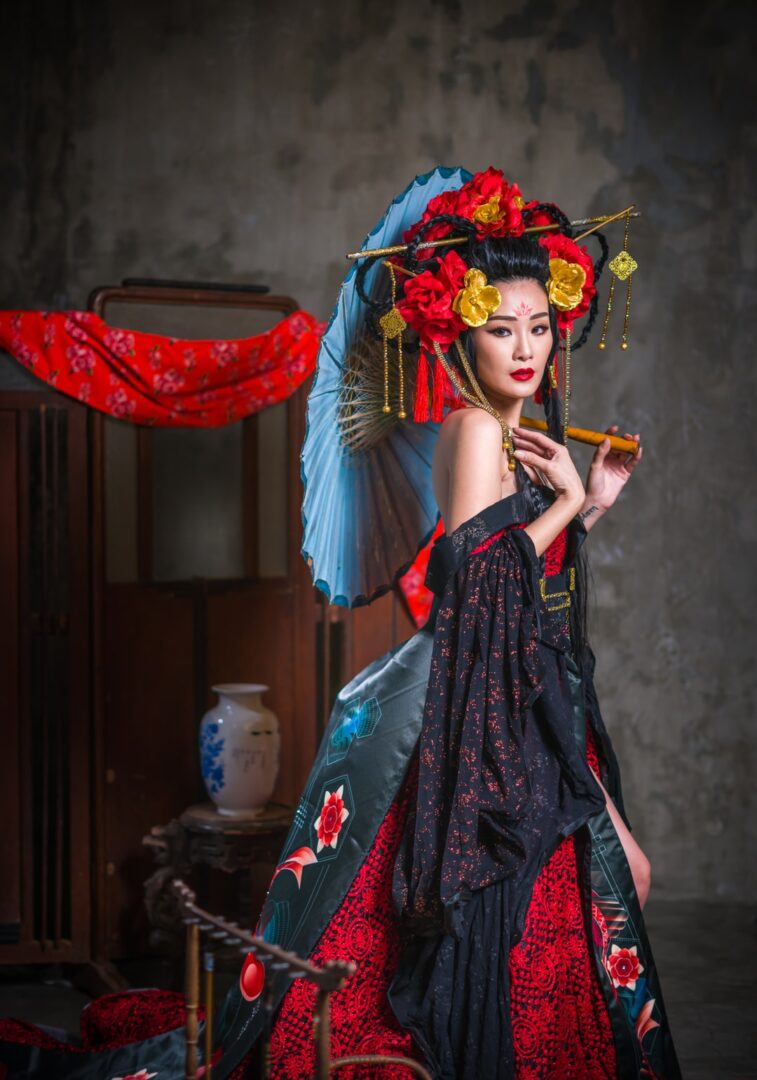 japonesa vestida de gueixa com sombrinha azul flores vermelhas no cabelo maquiada